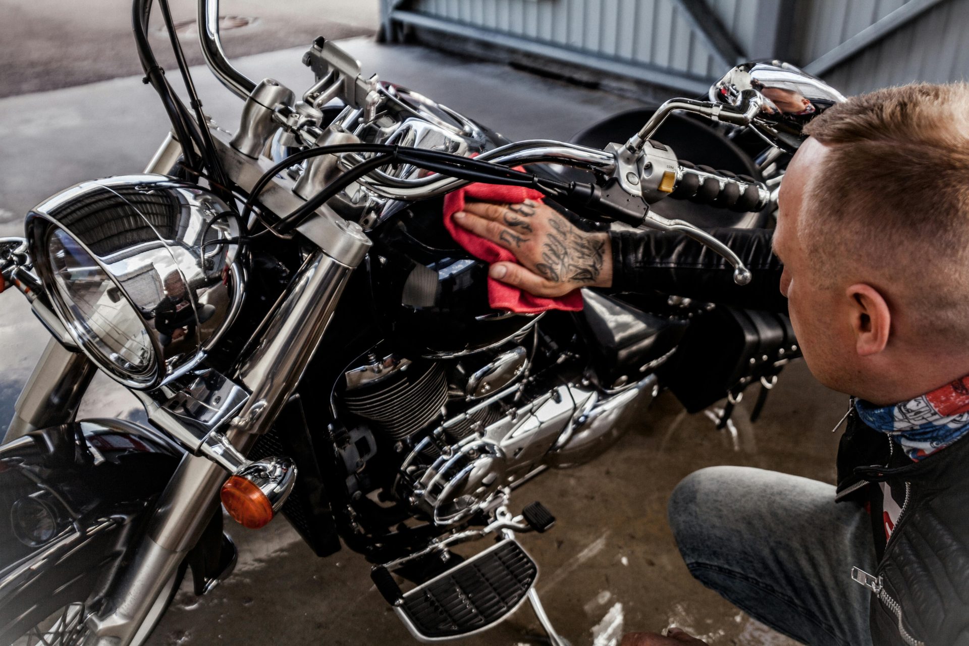 Adult man polishing a shiny motorcycle with a red cloth, indoors.