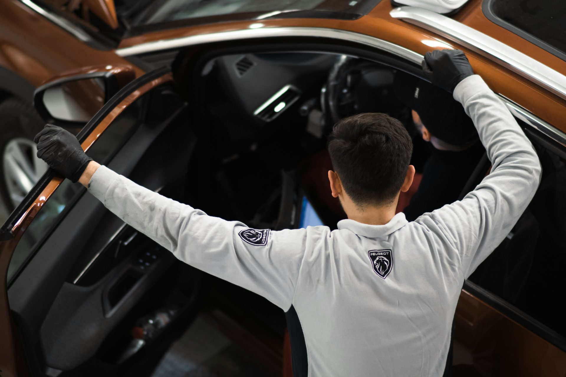 A man standing next to a brown car